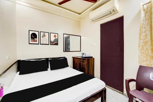 a bedroom with a bed and a black door and a chair at Hotel O MA Chidambaram Stadium Formerly Sarvanas Park in Chennai