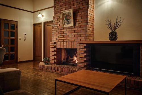 a living room with a brick fireplace with a tv at Villa Noël Hakone Chimney Luxury Onsen & Sauna Retreat in Hakone