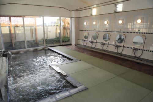 a bathroom with a pool of water and urinals at Hotel New Kotobuki in Matsumoto