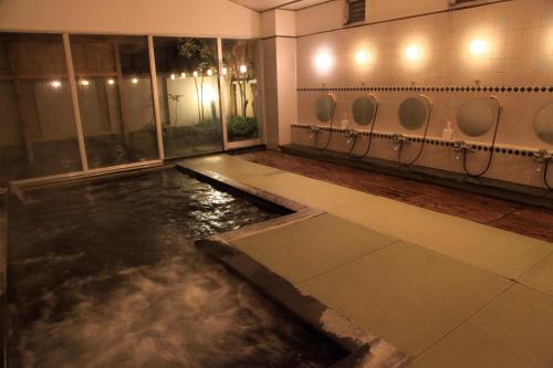 a room with a pool of water in a bathroom at Hotel New Kotobuki in Matsumoto