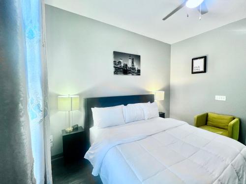 a bedroom with a white bed and a yellow chair at Uptown Charlotte Modern Stay 2BR in Charlotte
