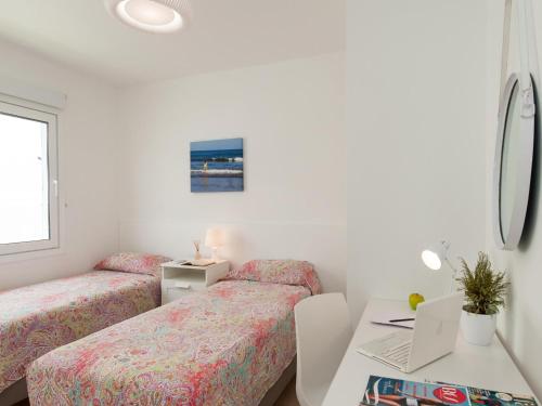 a bedroom with two beds and a desk with a laptop at Bungalow Playa del Inglés JFGI by VillaGranCanaria in Playa del Ingles