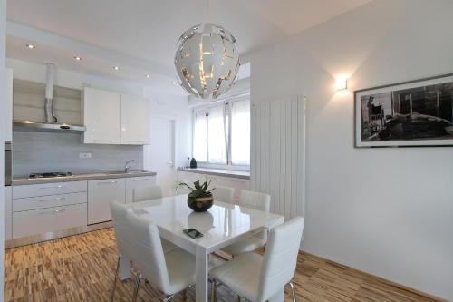 a white kitchen with a white table and white chairs at Attico Stema Luxury in Misano Adriatico