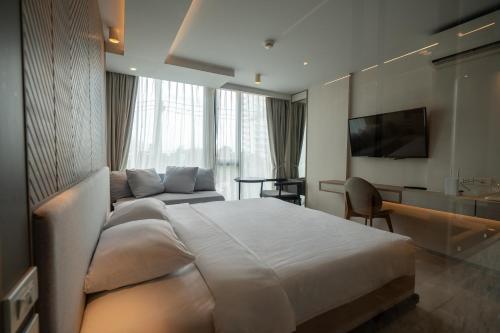 ein Hotelzimmer mit einem großen Bett und einer Couch in der Unterkunft Bluphere Residence by Prop Hopper in Na Jomtien