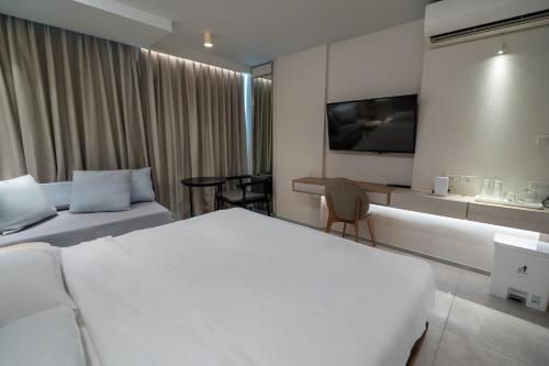 ein Hotelzimmer mit einem Bett und einem Fernseher an der Wand in der Unterkunft Bluphere Residence by Prop Hopper in Na Jomtien