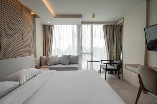 a hotel room with a bed and a couch and a table at Bluphere Residence by Prop Hopper in Na Jomtien