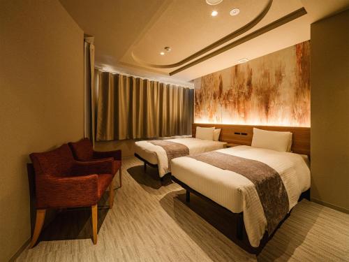 una habitación de hotel con dos camas y una silla en Hotel Espasion Pontocho, en Kioto