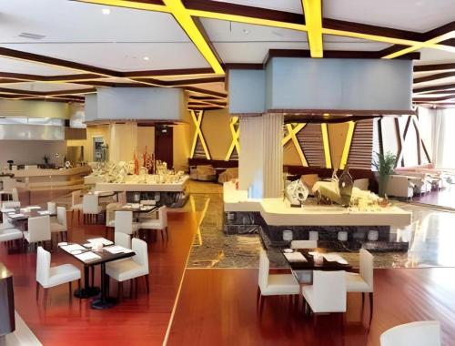 een restaurant met witte tafels en witte stoelen bij Ramada Plaza by Wyndham Shaowu in Liaojiapai
