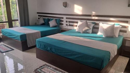a bedroom with two beds with blue and white pillows at Indunil Family Residence With Pool Hiriketiya in Dickwella