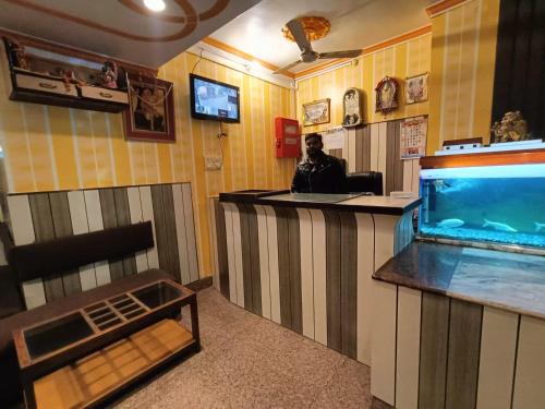 a man sitting at a bar with a fish tank at Hotel AMAN PALACE in Prayagraj