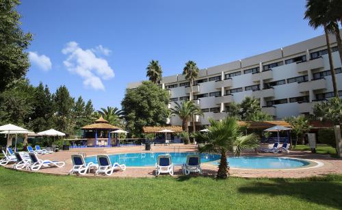 a hotel with a swimming pool and lounge chairs at Atlas Orient in Oujda