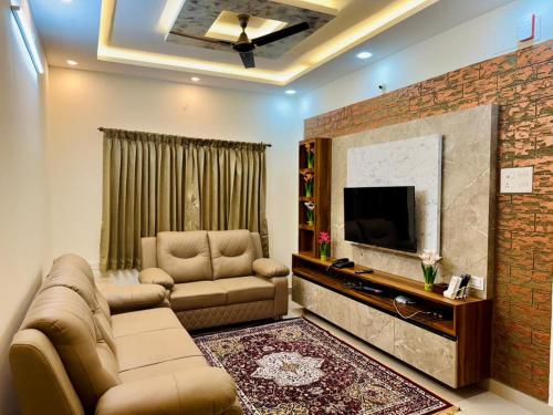 a living room with a couch and a flat screen tv at Marvee Luxus Stay in Coimbatore