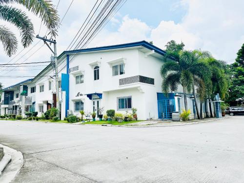 ein weißes Haus auf einer Straße mit Palmen in der Unterkunft KGH Villa Rental in Cuayan