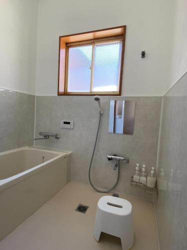 ein Badezimmer mit Badewanne, Toilette und Fenster in der Unterkunft あかり庵 in Iki