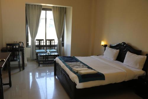 a bedroom with a large bed with a desk and a window at Hotel Rangbhawan Kumbhalgarh in Kelwāra