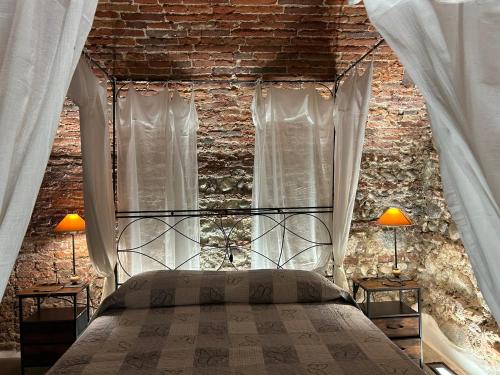 a bedroom with a brick wall with a bed and two lamps at Taverna La Torre in Bassano del Grappa