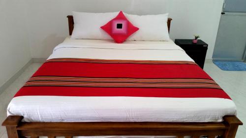 a bed with a red and white comforter at Radha Tourist Home in Polonnaruwa