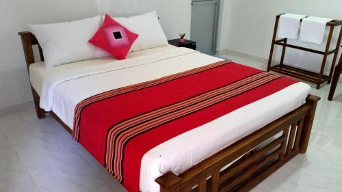 a bedroom with a bed with a red pillow on it at Radha Tourist Home in Polonnaruwa