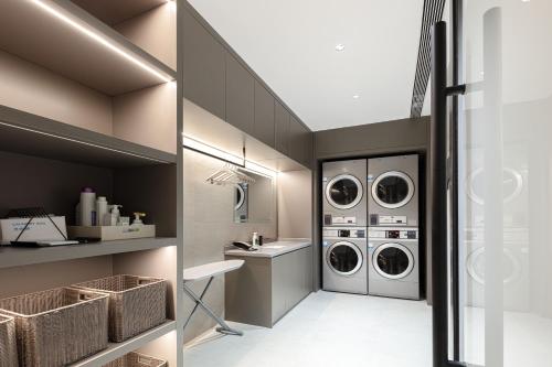 een wasruimte met 3 wasmachines en een wastafel bij Atour Light Hotel Cixi Sports Center Xinhefang in Hushan