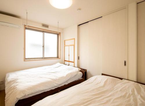 two beds in a room with a window at Elle Maison大森 102 in Tokyo