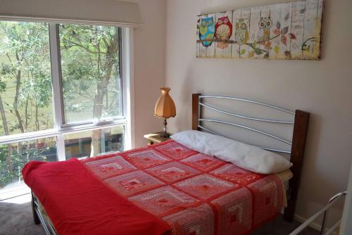 une chambre avec un lit rouge et une fenêtre dans l'établissement Tranquil Beach Escape, à Evergreen