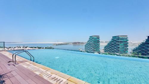 a swimming pool with a view of the ocean and buildings at Modern 3 Bedroom Al Hadeel West Side Al Rahah Beach in Abu Dhabi