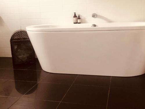 a bathroom with a white tub and a sink at Wattle Seed Beach House in Evergreen