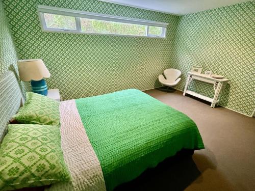 a green bedroom with a bed and a window at Wattle Seed Beach House in Evergreen