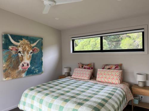 a bedroom with a bed and a painting of a cow at Ngurra in Evergreen