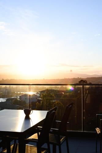 a table and chairs on a balcony with the sunset at Tamar Views in Inveresk