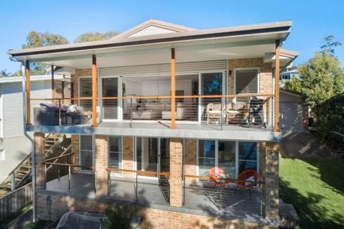 a house with a large deck with a patio at Lakeside - relaxed 3 BR waterfront retreat in Burrill Lake