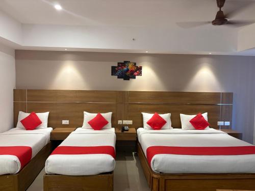 two beds in a room with red pillows at Hotel Mangala Temple View in Guruvāyūr
