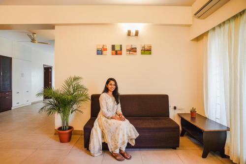a woman sitting on a couch in a living room at FabHotel Home Tree Service Apartment - Nr Anna Tower in Chennai