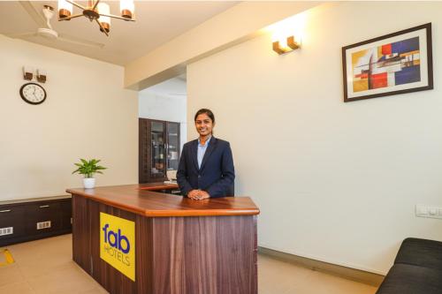 a man standing at a podium at a desk at FabHotel Home Tree Service Apartment - Nr Anna Tower in Chennai