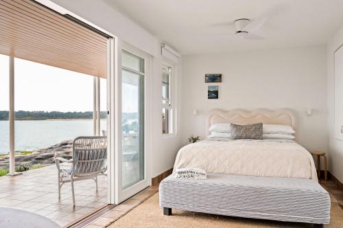 a bedroom with a bed and a chair and a window at Fogo @ Ethel & Ode’s in Bundeena