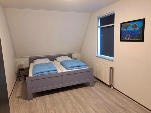 ein Schlafzimmer mit einem Bett mit blauen Laken und einem Fenster in der Unterkunft Comfortabel landhuis voor rust en ontspanning in Schoonloo