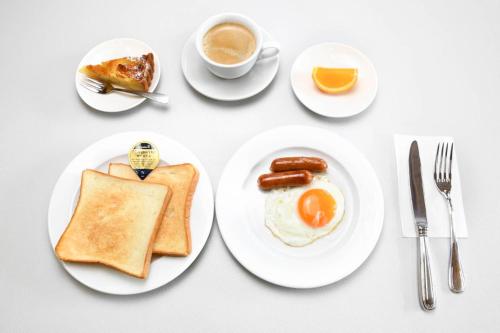 uma mesa com pratos de café da manhã e uma xícara de café em ビジネスホテル旅館本陣 em Kisarazu