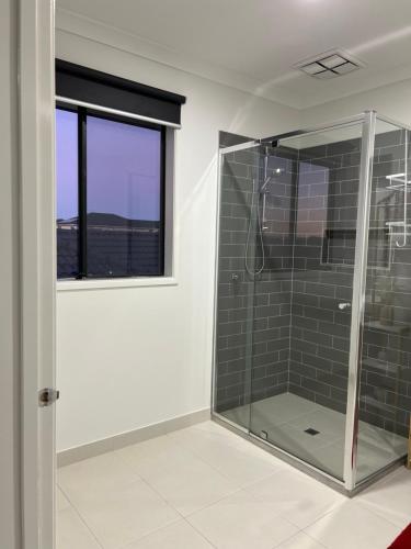 a bathroom with a glass shower and a window at Mahzan on Kilcunda - Ensuite 1 in Truganina