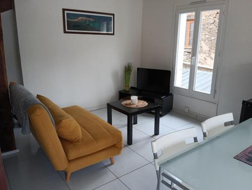 een woonkamer met een bank en een tafel bij Petite maison Quartier Ste Croix in Josselin