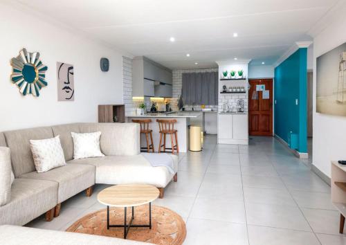 a living room with a couch and a kitchen at Neptunes Hideaway in Jeffreys Bay