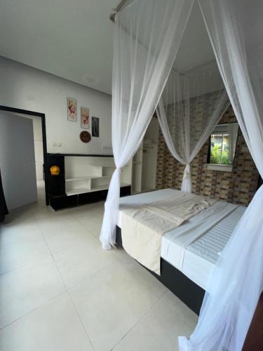 a bedroom with a bed with white drapes at bali amed feel home in Amed