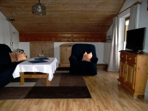 a living room with a table and chairs and a tv at Dachgeschosswohnung Mit Toller Aussicht Vom Balkon in Bayersoien