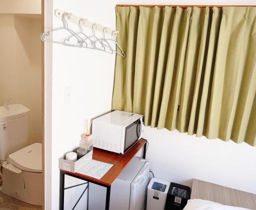 a room with a microwave on a table next to a toilet at 青麦旅館台東店 in Tokyo