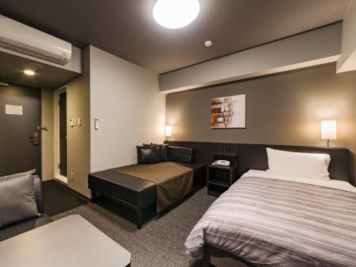 a hotel room with a bed and a couch at Hotel Route-Inn Grand Ota Ekimae in Ota
