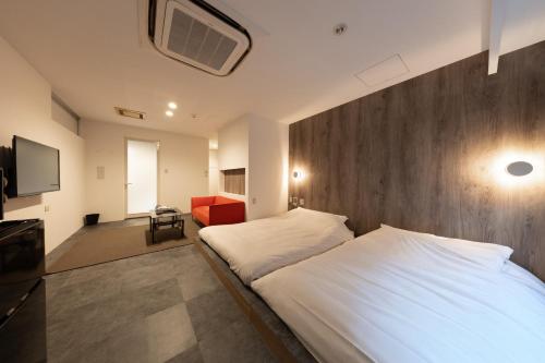 een slaapkamer met een groot wit bed en een rode stoel bij Huntelia Matsuyama in Matsuyama
