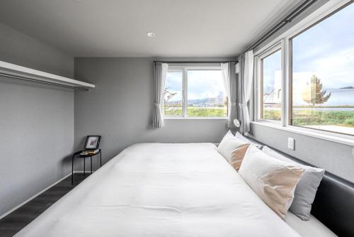 a large white bed in a room with two windows at Orvia Yig Villa in Furano
