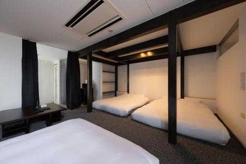 two beds in a hotel room with twothirdsessions at Huntelia Matsuyama in Matsuyama