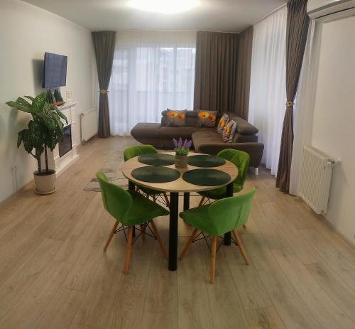a living room with a table and green chairs at Penthouse City View Infinity in Braşov
