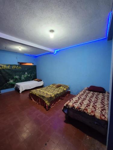 - 2 lits dans une chambre avec un mur bleu dans l'établissement Maya'n House, à Santiago Atitlán