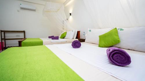 Dos camas en una habitación con verde y blanco. en Woodsy Villa, en Sigiriya